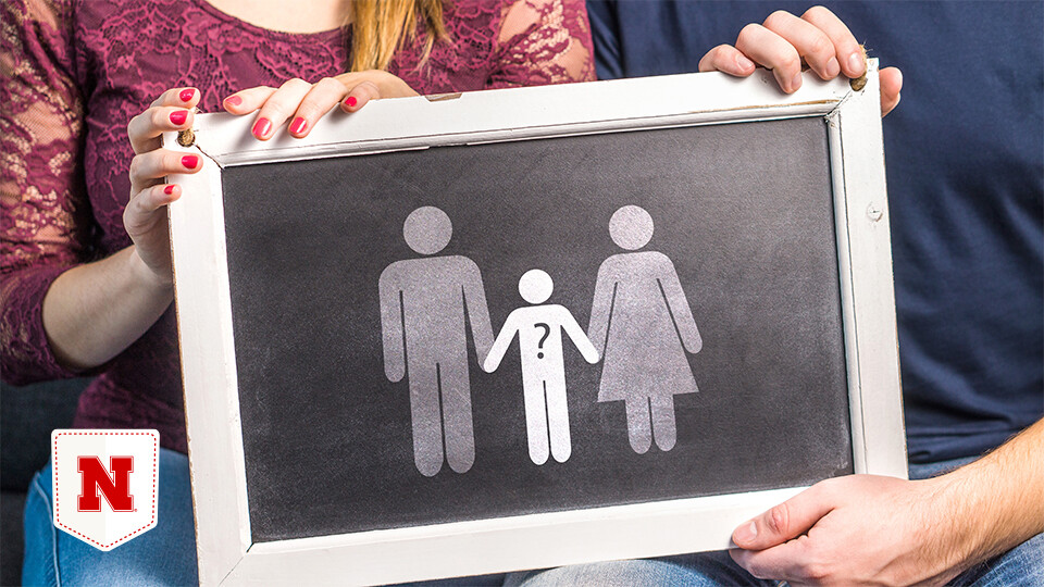 A couple holds a stick figure picture of a family.