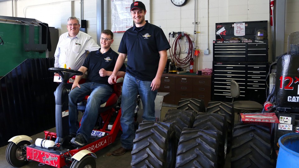 Roger Hoy (from left), Caleb Lindhorst and Luke Prosser show off a tractor designed by students for a 2014 engineering competition. Lindhorst was involved in a December 2013 auto accident and support from Hoy and Prosser has helped him return to classes at UNL.