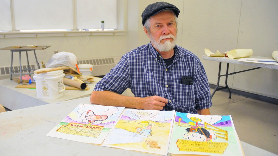 Rod Roth, custodian specialist, sits in a Richards Hall studio with three of his Humpty Dumpty art prints. Roth recently expanded his art from creating medieval armor by hand to drawing and painting.