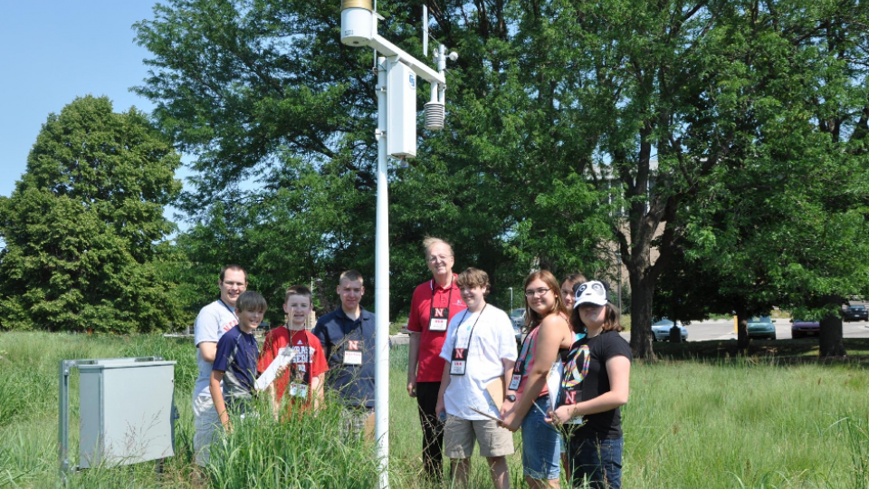 Ken Dewey and youth examine a weather monitoring station during the 2012 weather camp on East Campus.