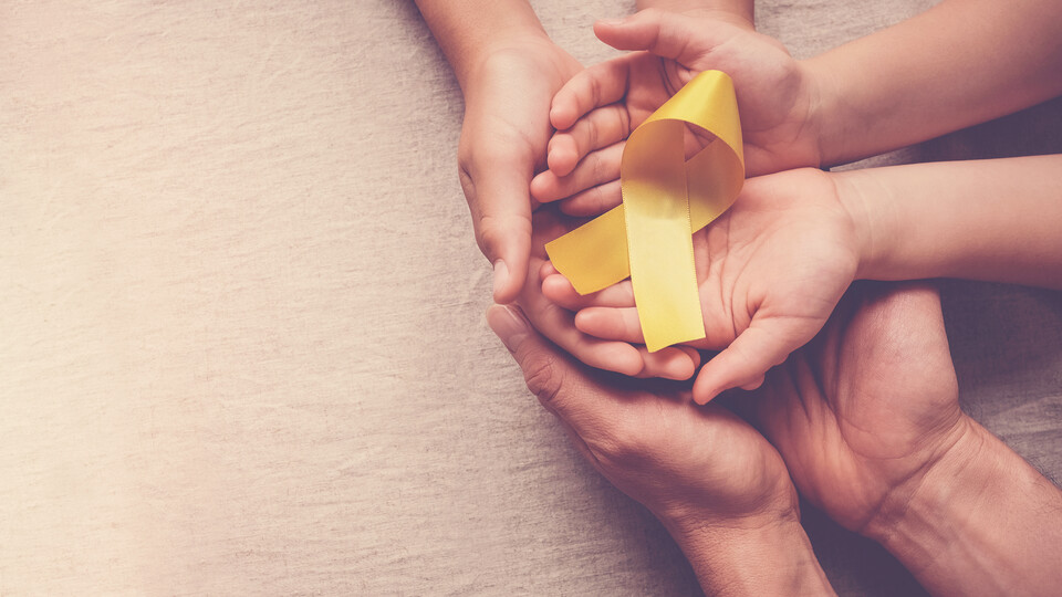 A yellow suicide awareness ribbon is held in enjoined hands