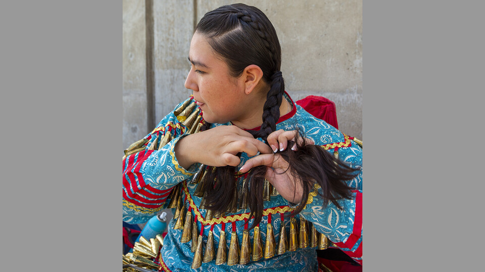 Alicia Scholfield braids her hair before the start of the UNITE powwow. Scholfield's family traveled from Kansas to attend.