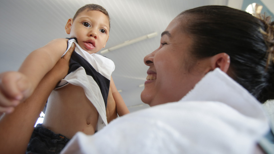 A child with microcephaly is held by a caregiver in a Brazil facility that cares for people affected by congenital zika syndrome.