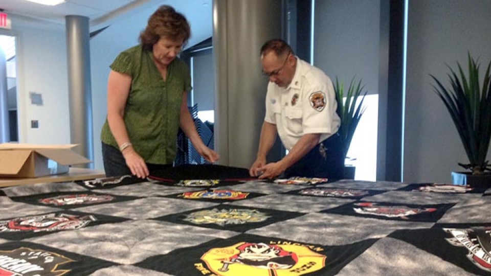 Carolyn Ducey, curator of collections at the International Quilt Study Center and Museum, and fire inspector Rick Campos examine the Lincoln Fire and Rescue T-shirt quilt that will be revealed during First Friday events on Nov. 6.