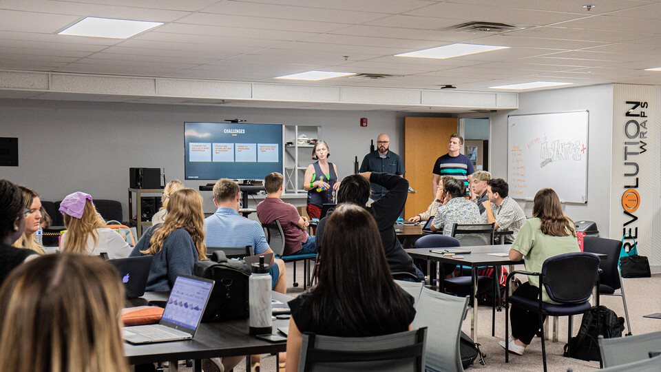 Three representatives of Swanson Russell — two men and a woman — speak to a room of a dozen-plus students in the Jacht Ad Agency.