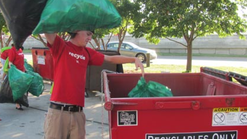 A volunteer places recyclable materials in a bin during the 2011 game against Michigan State.