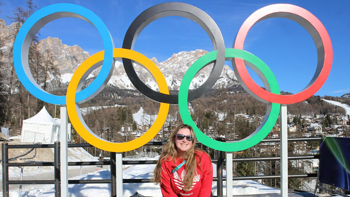 Aeriel Frey, a University of Nebraska-Lincoln 2024 Alumna, posing in front of the Olympic Rings in Cortina, Italy.