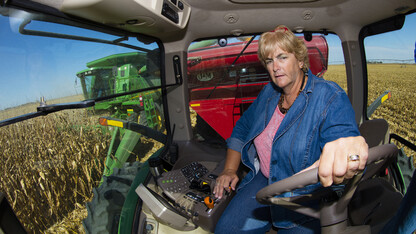 Sharon Portenier drives the tractor pulling the grain wagon. The Portenier farm is located near Harvard, Nebraska.