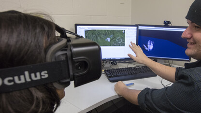 Zach Day demonstrates his work with visual reality headsets that will allow participants to tour ruins around the world. He is demonstrating an add on that allows the users hands to be part of the VR and manipulate objects in the program.