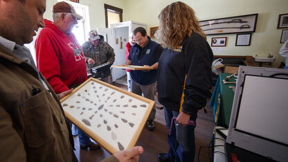 Dennis Kuhnel (center) and Matt Douglass look over a collection brought in by Chuck Anders (in the Husker sweatshirt), and his daughter Jennifer Peters (right), during the Artifacts Roadshow event on Oct. 7 in Mullen.