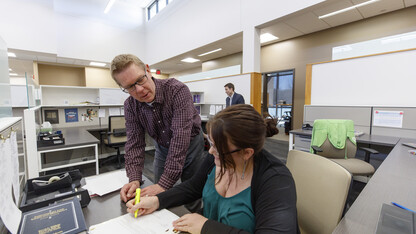 Professor Kevin Ruser and third-year law student Kelsey Heino review a case in the new workspaces of the Marvin and Virginia Schmid Clinic Building. Professor Ryan Sullivan is in the background. 