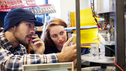 Mike Cox and Elizabeth Balerud watch as a lightweight boom and mock solar panel deploy from a space tool they helped build. 