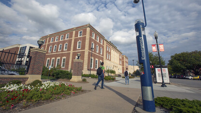 Students walk by the blue public safety phone on the south side of the Nebraska Union on Oct. 20. Due to technology advances and replacement costs, all but two of the phones are being removed from the university.