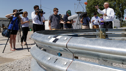 Bob Bielenberg (right) explains the new highway barrier being tested to the media and the NASCAR tour group.