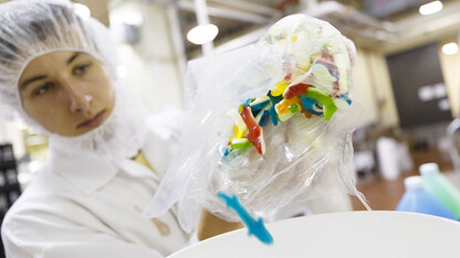 Alec Alvarez, a senior food science and technology major and student employee in the Dairy Store, measures shark gummy candies in a bucket prior to adding it to the Shark Week ice cream mixture.