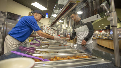 Kim Scerini, a team leader in the Harper Dining Center, serves a pork chop and potato wedges to Gabe Walmsley at the allergen-free food station in Harper Dining Center. The allergen-free option is available at lunch on Wednesdays this semester, but will expand to all meals in January.