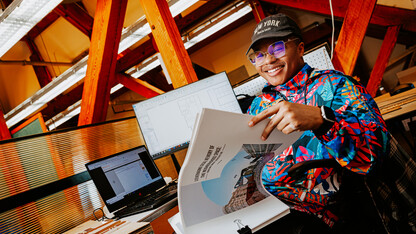 Jeremiah Brown smiles for a photo at a desk in Architecture Hall