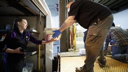 Ed Kearney receives a package from FedEx's Mary Chandler.  Package delivery has been consolidated at the Facilities Management Shops on north 22nd St. There, the packages are sorted, logged in and the recipients notified to pick up the package or have it stored until they return. 