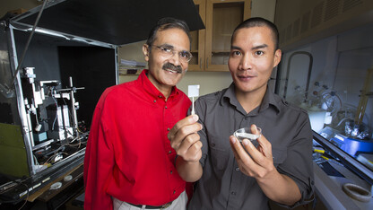 Ravi Saraf (left) and fellow researcher Chieu Van Nguyen, who is holding up a thin membrane on a slide cover.