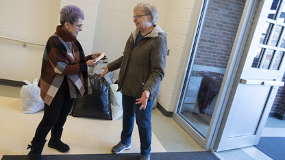 Dee Ebbeka hands Linda Kern, of Clinton Elementary School, the last of the Caring for Clinton donations Dec. 6, 2019, at the school on Holdrege Street.