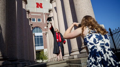 Rose Wehrman of Kenesaw is photographed by Sarah Schilling of Omaha. The two graduates borrowed a cap and gown from a friend who graduated last year to take photos of each other on campus April 30. Wehrman earned a Bachelor of Arts with distinction, and Schilling earned a Bachelor of Science in Business Administration with high distinction.