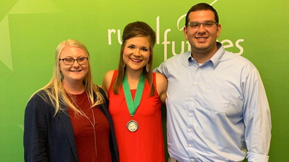 Fellows program leaders Amber Ross (left) and Andrew Ambriz (right) stand with one of their four student fellows, Megan Coan (middle), during a celebration at the end of the 2019 program.