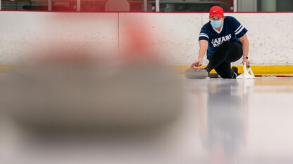 A curler throws the curling stone down the ice lane.