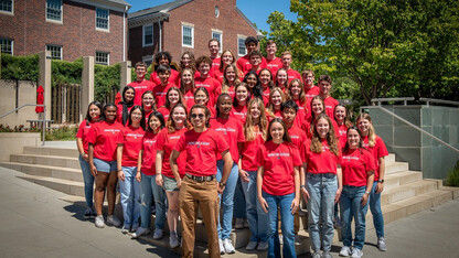 A large group of Nebraska Engineering students, wearing red T-shirts, stands outside of the Wick Alumni Center.