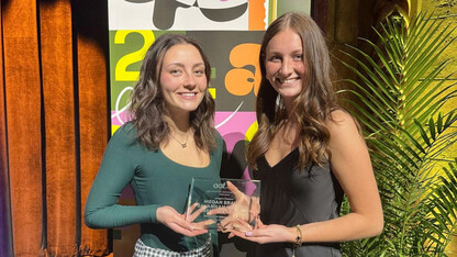 Two young women hold a glass award.