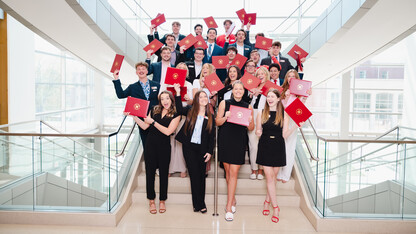 About two dozen university students pose on a staircase with their certificates of sales excellence.