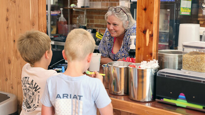 A woman serves ice cream to two boys.