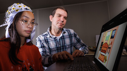 Kevin Pitt, assistant professor of special education and communication disorders, demonstrates an electrode cap in the AAC Translation Lab with Aliyah Muniz, a senior speech-language pathology major.