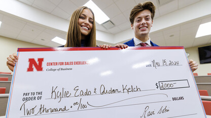 Husker students Kylie Eads and Aidan Kelch pose with a giant check for $2,000.