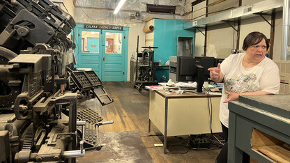 Tonya Evans, owner and publisher of the Colfax County Press, leans on a table across from an old printing press. helps put out the paper from an old building on the main street in Clarkson, where a lot of the original printing press machinery is still housed. The small paper is one of 203 state and local news organizations in Nebraska. (Jessica Walsh/College of Journalism and Mass Communications)