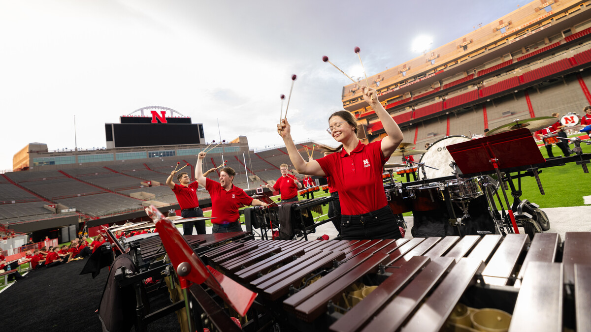 Members of the pit raise their mallets amid a percussion performance during the Cornhusker Marching Band’s annual exhibition concert Aug. 22 at Memorial Stadium.