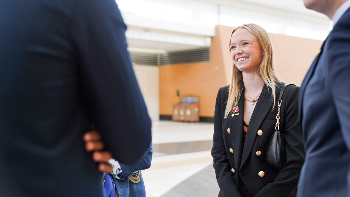 Peyton Cusick, a junior PGA golf management major, smiles as she stands in a small group at the 108th PGA Annual Meeting in Grand Rapids, Michigan, in November 2024. She is wearing a black blazer with gold buttons.