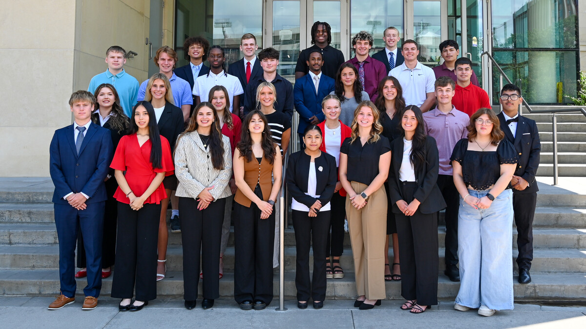 Thirty college students in dress clothes pose for a photo on the west steps of Howard L. Hawks Hall.