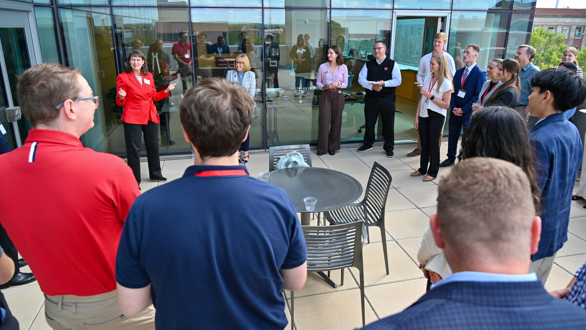 A dozen or so people stand on a patio at Howard L. Hawks Hall.
