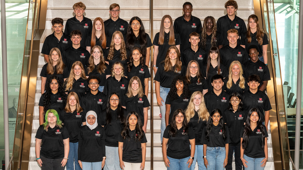 Forty Husker students in black polo shirts — all members of the 2025-26 cohort of the Peter Kiewit Foundation Engineering Academy — pose for a photograph on a staircase in Kiewit Hall.