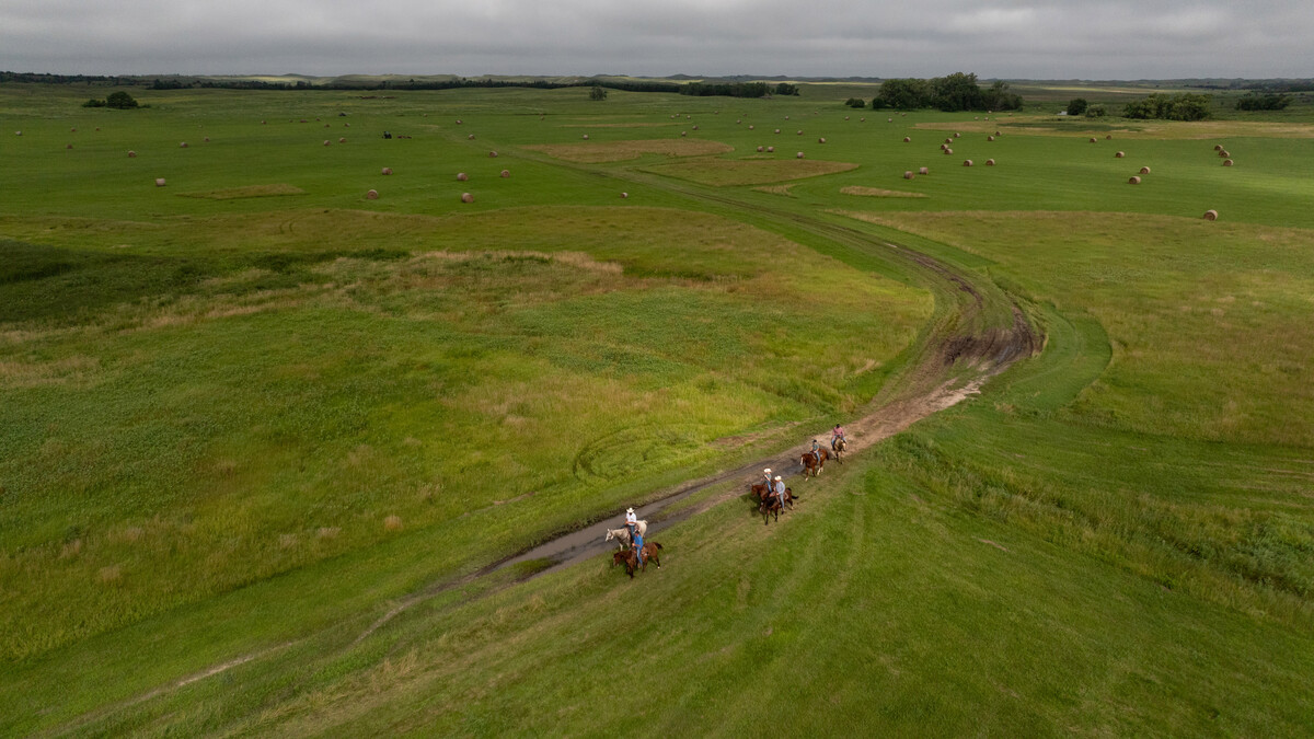 An aerial photo of six ranchers riding horses in the Nebraska Sandhills.