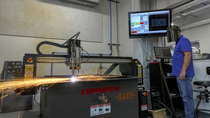 Jerry Reif, shop manager at Nebraska Innovation Studio, watches as a plasma cutter cuts through steel.