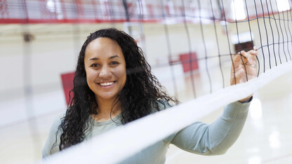 Mariah Bullock stands in front of a volleyball net. 