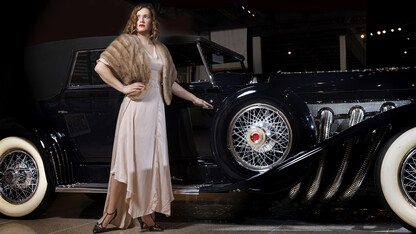 Anna Kuhlman evokes Hollywood glamour in this long 30s-style gown features bias cut panels and flowing sleeves in a soft pink. Paired with a vintage fur stole and T-strap heels.She poses next to a 1930 Duesenberg Model J at the Speedway Motors Museum of Speed. Kuhlman, who received her masters degree in May, researched fashion in the 1930s both in film and what was available in Nebraska.