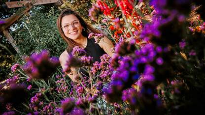 Isabella smiles for a photo surrounded by flowers on East Campus