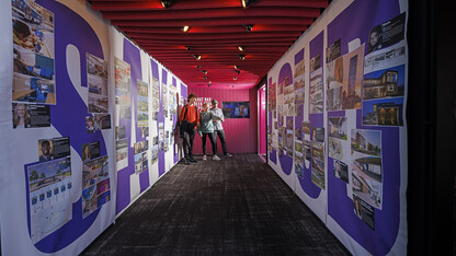 Three members of the campus community look over a "Say it Loud" traveling exhibition, which features diverse designers. Individuals featured include two current UNL students and 24 alumni.