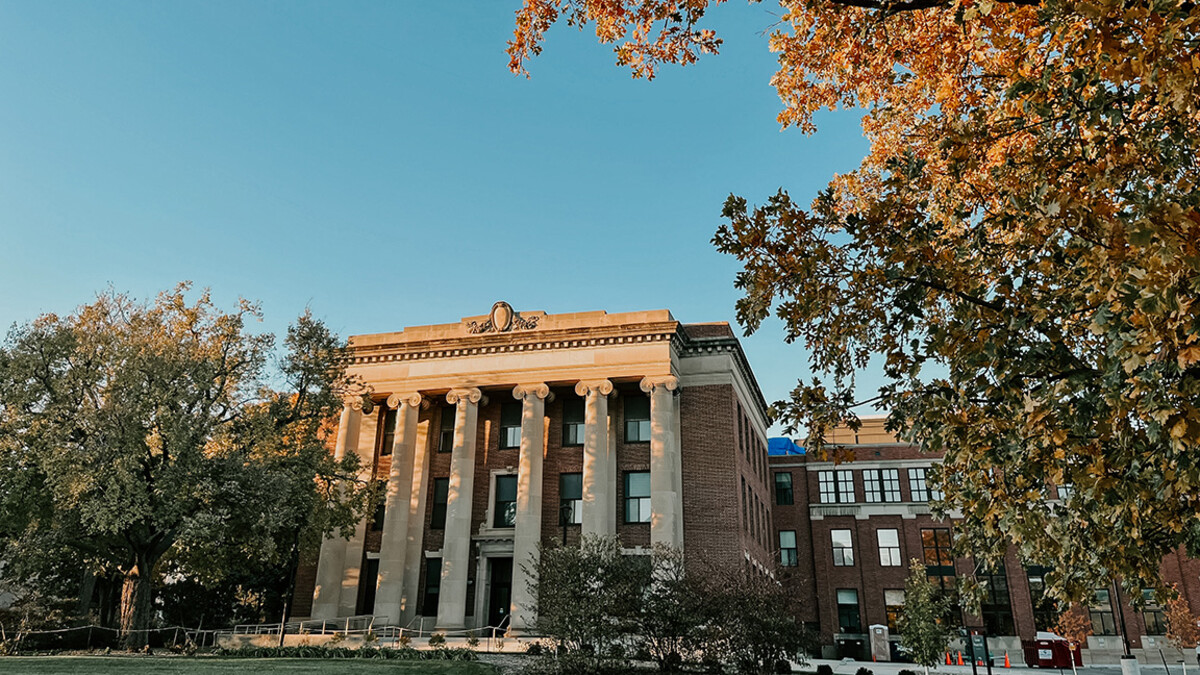 Pound Hall is framed by gold leaves and a blue sky.