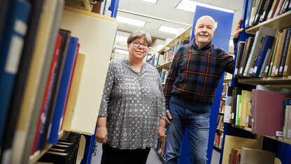 Joanie Barnes (left) and Tom McFarland stand in the stacks of Love Library.