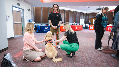 Photo Credit: Garrett Stolz // Brett Neely smiles for a photo as Marko receives some attention from Huskers during a Pawp Up event on campus.