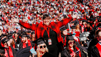 Annette Wetzel smiles for a photo with her arms outstretched in a sea of Husker grads before undergraduate commencement