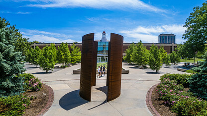 Blue summer skies, trees and sculpture frame the Love Library cupola